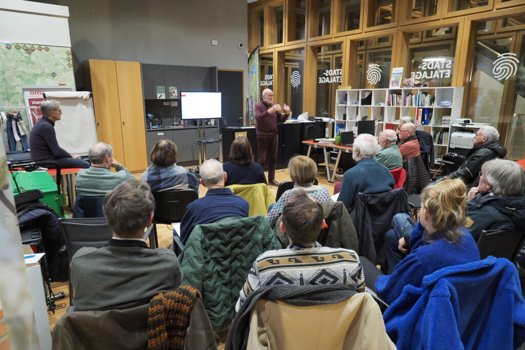 Het publiek kijkt in het Duurzaamheidscentrum naar de informatieavond gegeven door energiecoaches Peter Alkemade en Ton Holtslag